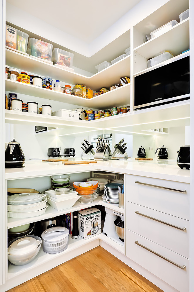 Photo of a contemporary kitchen pantry in Melbourne with open cabinets, white cabinets and mirror splashback.