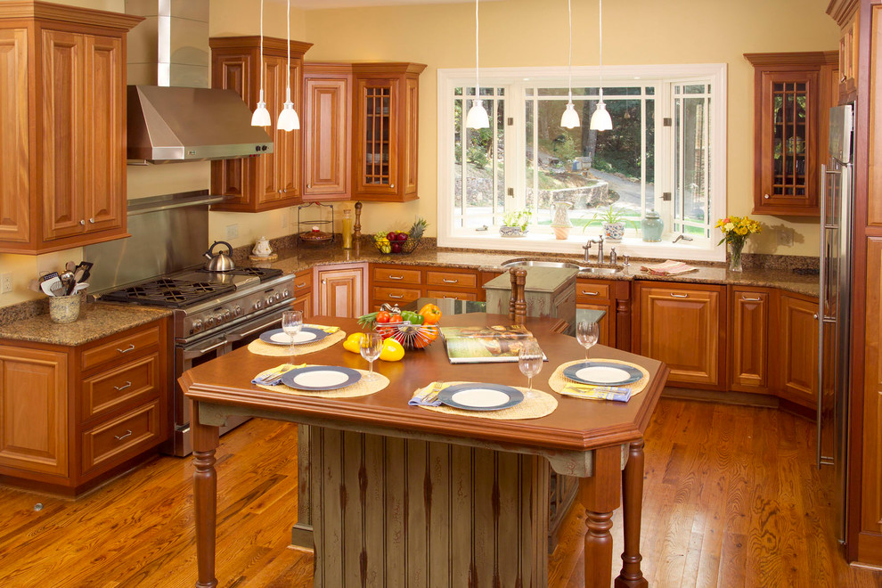 Foto på ett mycket stort amerikanskt kök, med en nedsänkt diskho, skåp i slitet trä, granitbänkskiva, vitt stänkskydd, rostfria vitvaror, ljust trägolv och flera köksöar