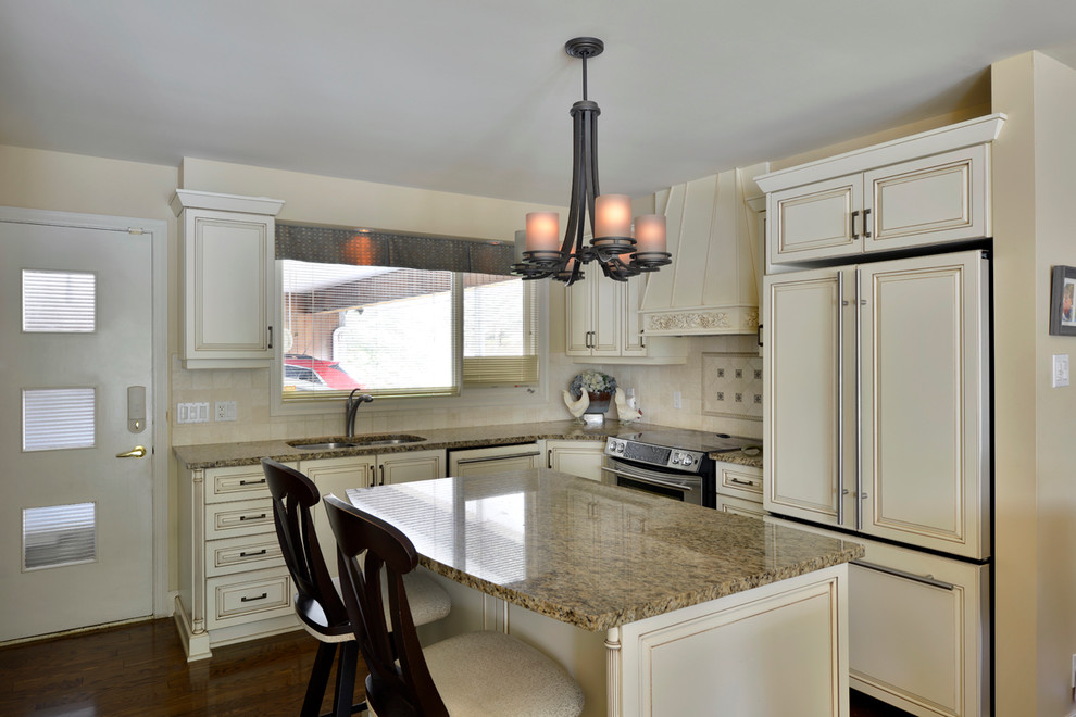 Eat-in kitchen - mid-sized traditional l-shaped medium tone wood floor eat-in kitchen idea in Ottawa with an undermount sink, shaker cabinets, white cabinets, granite countertops, beige backsplash, ceramic backsplash, black appliances and an island