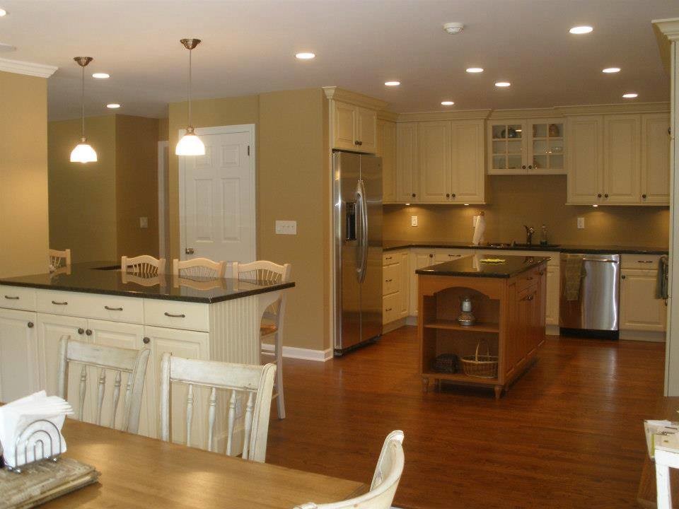 Medium sized rural u-shaped kitchen/diner in New York with a submerged sink, raised-panel cabinets, white cabinets, stainless steel appliances, dark hardwood flooring and an island.