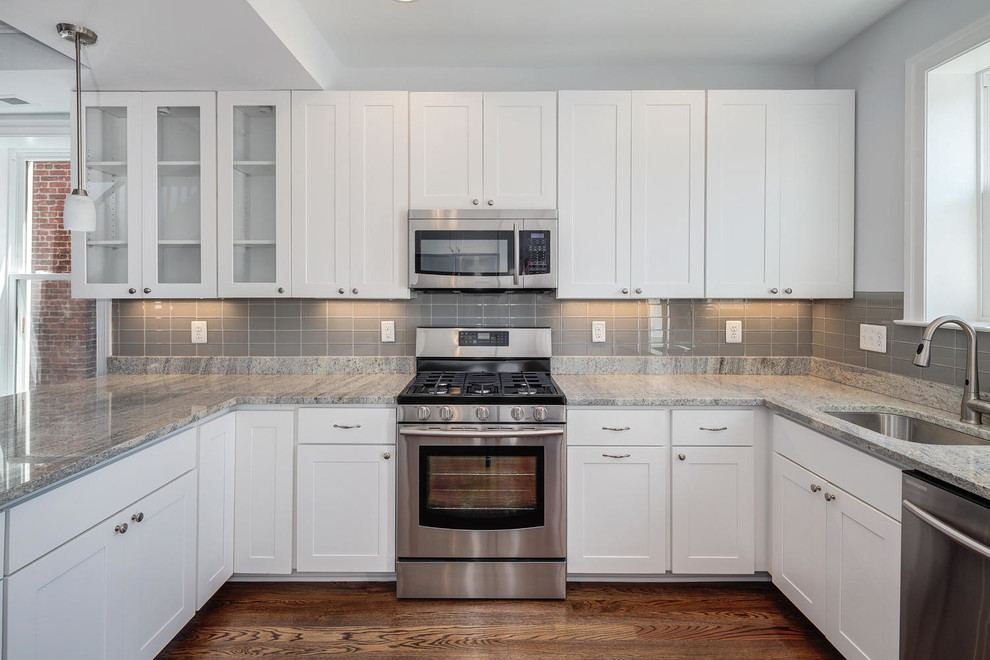 Inspiration for a mid-sized transitional u-shaped dark wood floor and brown floor enclosed kitchen remodel in DC Metro with an undermount sink, shaker cabinets, white cabinets, granite countertops, gray backsplash, porcelain backsplash, a peninsula and gray countertops