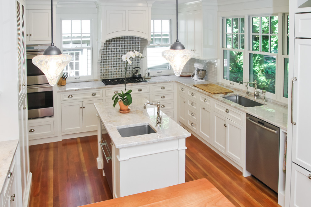 Inspiration for a mid-sized timeless u-shaped medium tone wood floor and brown floor eat-in kitchen remodel in Boston with an undermount sink, white cabinets, marble countertops, subway tile backsplash, stainless steel appliances, recessed-panel cabinets, white backsplash and two islands