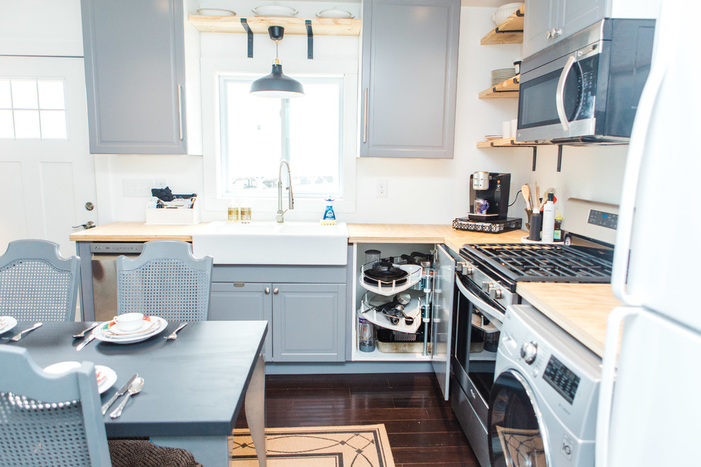 Inredning av ett eklektiskt litet kök, med en rustik diskho, luckor med upphöjd panel, grå skåp, träbänkskiva, rostfria vitvaror, mörkt trägolv och brunt golv