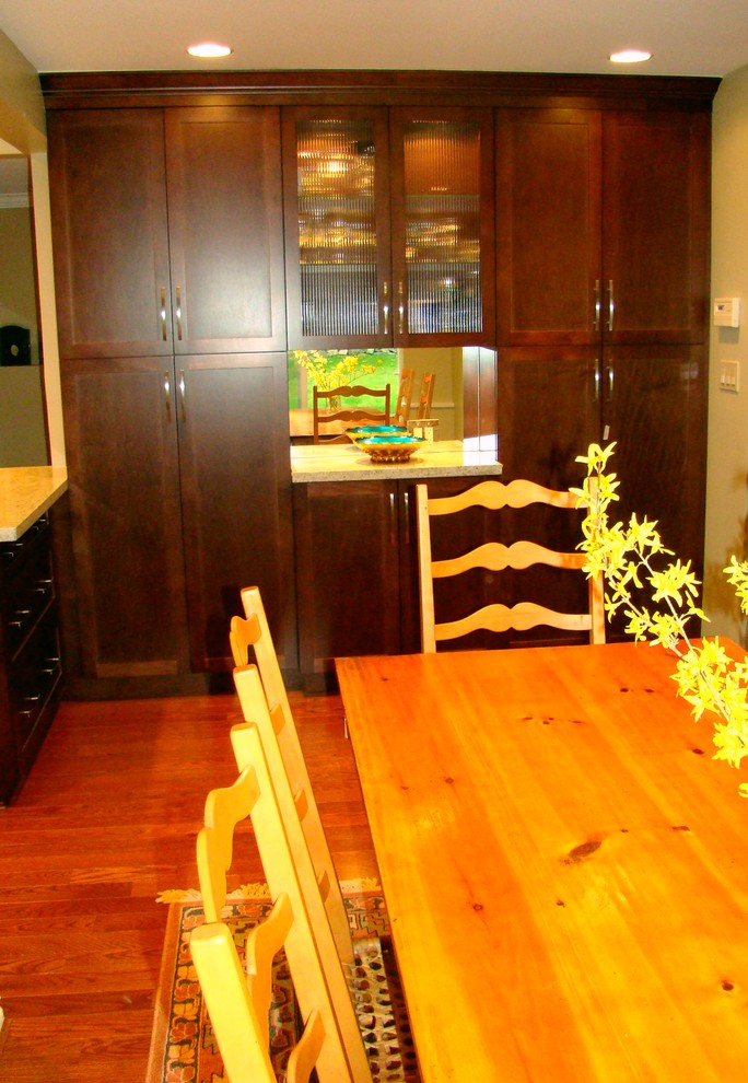 Cette photo montre une cuisine américaine chic en bois foncé de taille moyenne avec un placard à porte shaker, un plan de travail en quartz modifié, une crédence miroir, un sol en bois brun et une péninsule.