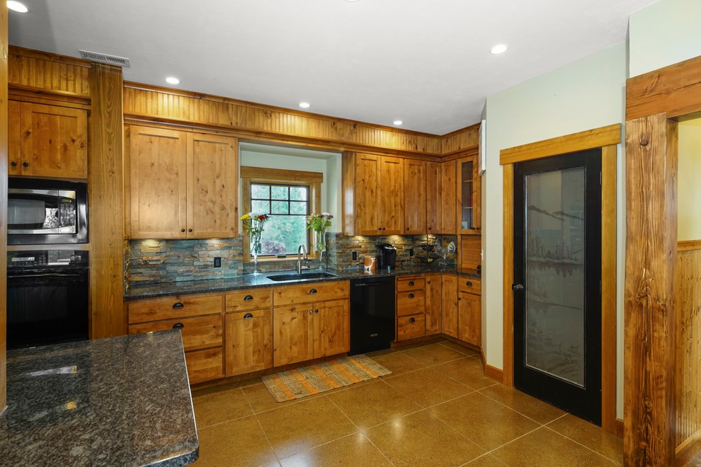 Exempel på ett stort amerikanskt flerfärgad flerfärgat l-kök, med en undermonterad diskho, luckor med infälld panel, skåp i slitet trä, granitbänkskiva, flerfärgad stänkskydd, stänkskydd i skiffer, svarta vitvaror, betonggolv, en köksö och beiget golv