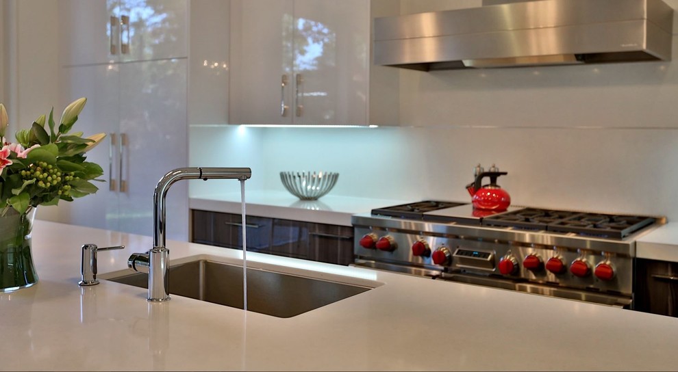 Design ideas for a medium sized contemporary l-shaped kitchen/diner in Toronto with a submerged sink, flat-panel cabinets, white cabinets, white splashback, stainless steel appliances, dark hardwood flooring and an island.