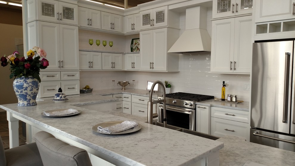 Klassisk inredning av ett mellanstort kök och matrum, med en dubbel diskho, vita skåp, marmorbänkskiva, vitt stänkskydd, stänkskydd i keramik, rostfria vitvaror och en köksö