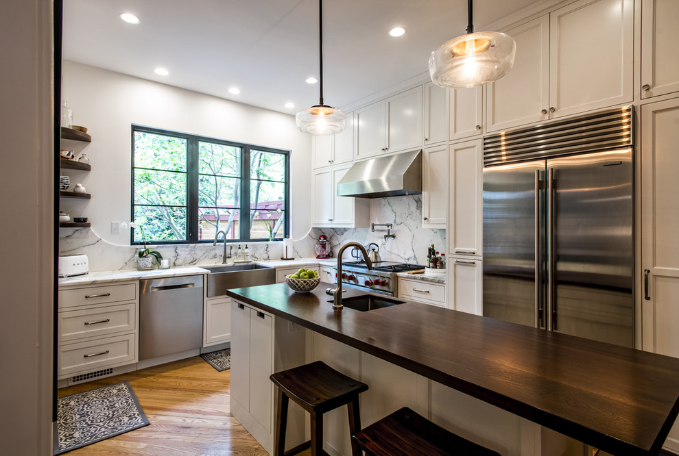 Enclosed kitchen - small transitional l-shaped medium tone wood floor enclosed kitchen idea in Louisville with a farmhouse sink, recessed-panel cabinets, white cabinets, marble countertops, white backsplash, marble backsplash, stainless steel appliances, an island and white countertops