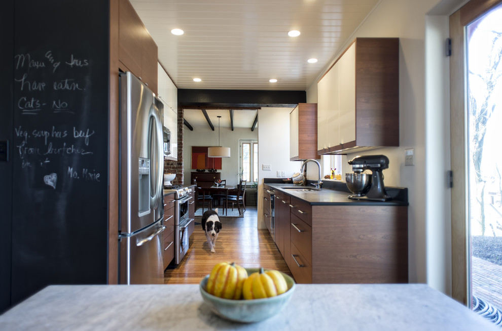 Esempio di una cucina minimalista con lavello sottopiano, ante lisce, ante in legno scuro e elettrodomestici in acciaio inossidabile