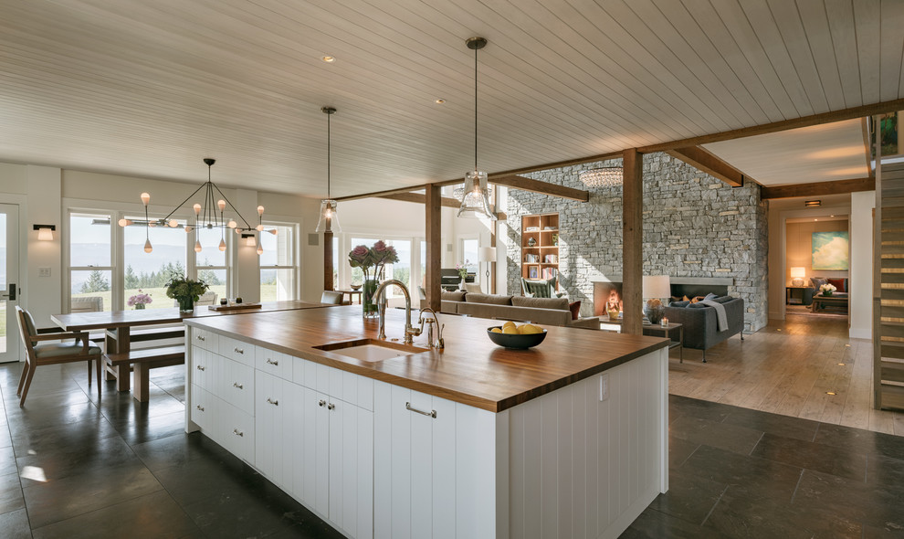 Foto de cocina lineal de estilo de casa de campo grande abierta con fregadero bajoencimera, puertas de armario blancas, encimera de madera, electrodomésticos de acero inoxidable, suelo de pizarra, una isla, suelo marrón y armarios con paneles lisos