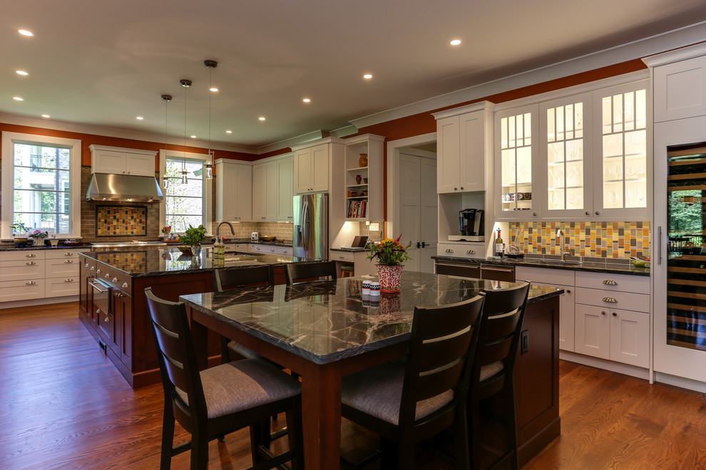 Cette photo montre une cuisine américaine tendance avec plan de travail en marbre, un électroménager en acier inoxydable, un sol en bois brun et îlot.