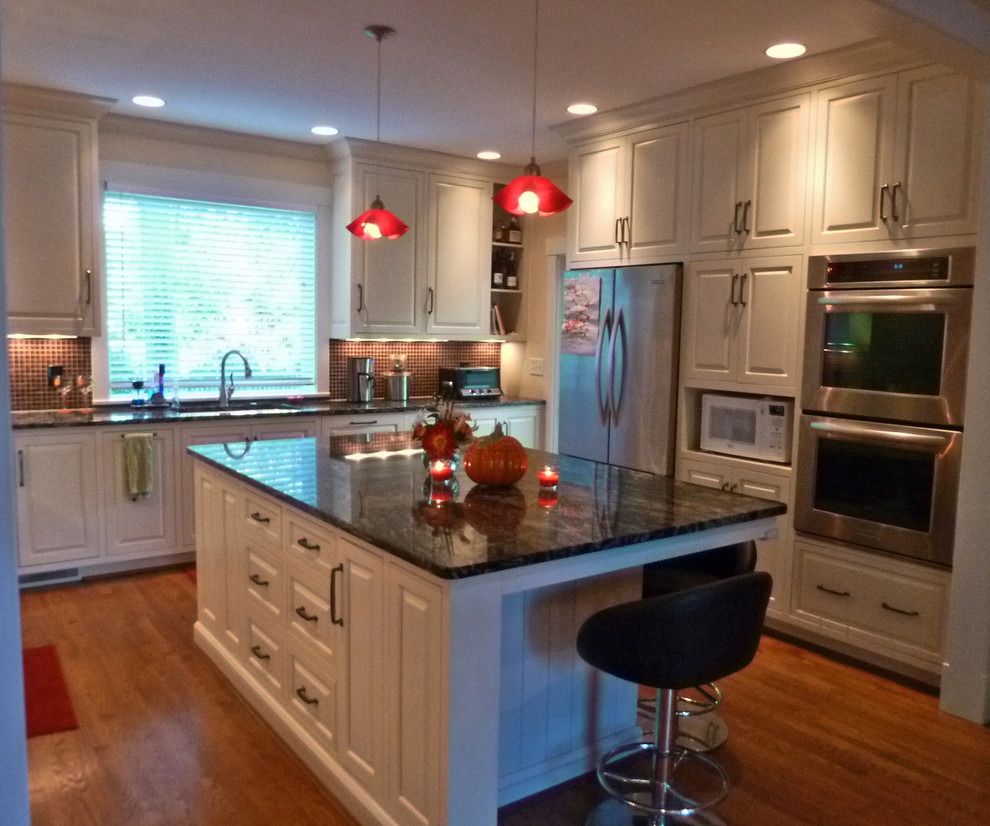 Modern inredning av ett avskilt, mellanstort u-kök, med en undermonterad diskho, luckor med upphöjd panel, vita skåp, granitbänkskiva, rött stänkskydd, stänkskydd i stenkakel, rostfria vitvaror, mellanmörkt trägolv och en köksö