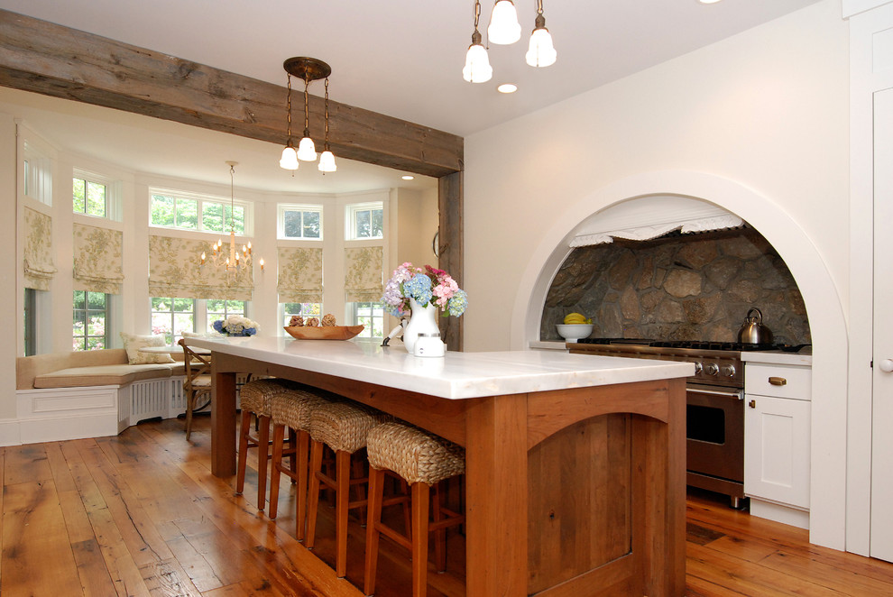 Exempel på ett stort rustikt kök, med rostfria vitvaror, luckor med infälld panel, vita skåp, en nedsänkt diskho, grått stänkskydd, mellanmörkt trägolv och en köksö