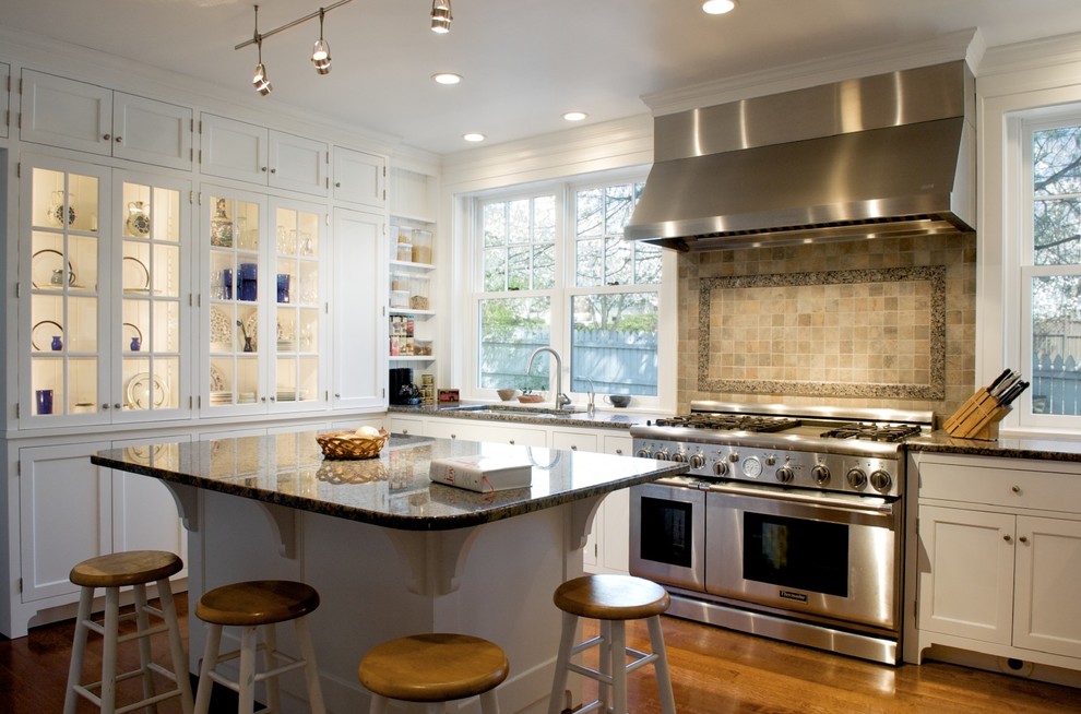 Diseño de cocina clásica con armarios tipo vitrina, electrodomésticos de acero inoxidable y encimera de granito