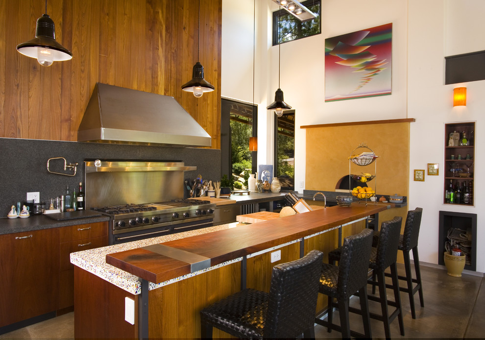 На фото: кухня в современном стиле с техникой из нержавеющей стали, деревянной столешницей и барной стойкой с