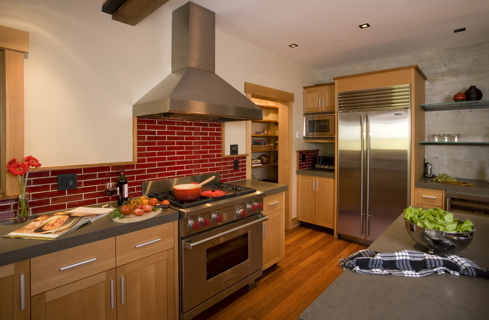 Diseño de cocina rústica con electrodomésticos de acero inoxidable, puertas de armario de madera oscura, encimera de cuarzo compacto, salpicadero rojo y salpicadero de azulejos tipo metro