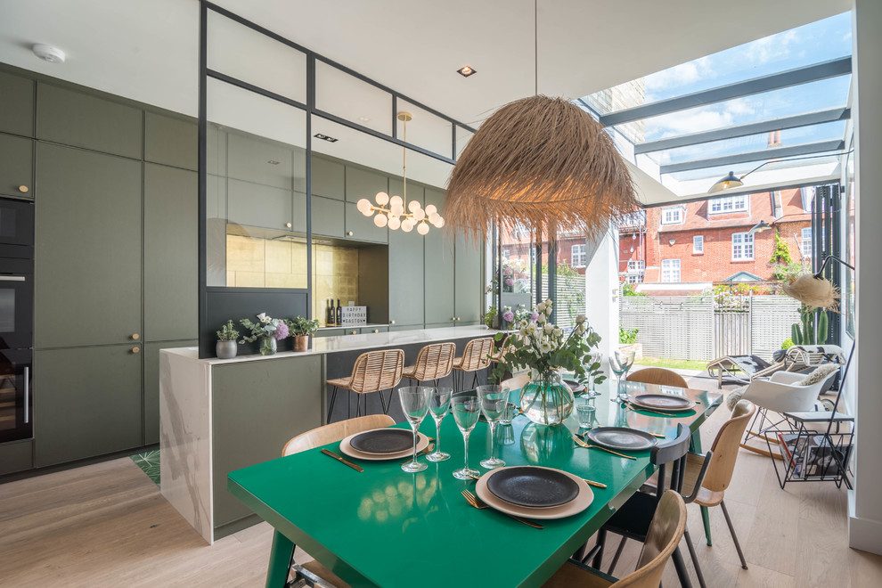 Foto på ett mellanstort funkis linjärt kök och matrum, med släta luckor, gröna skåp, marmorbänkskiva, stänkskydd med metallisk yta, ljust trägolv, en köksö och beiget golv