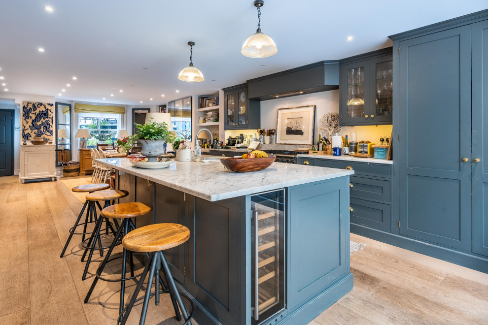 Foto di una cucina chic con lavello sottopiano, ante in stile shaker, ante blu, elettrodomestici neri, pavimento beige e top bianco