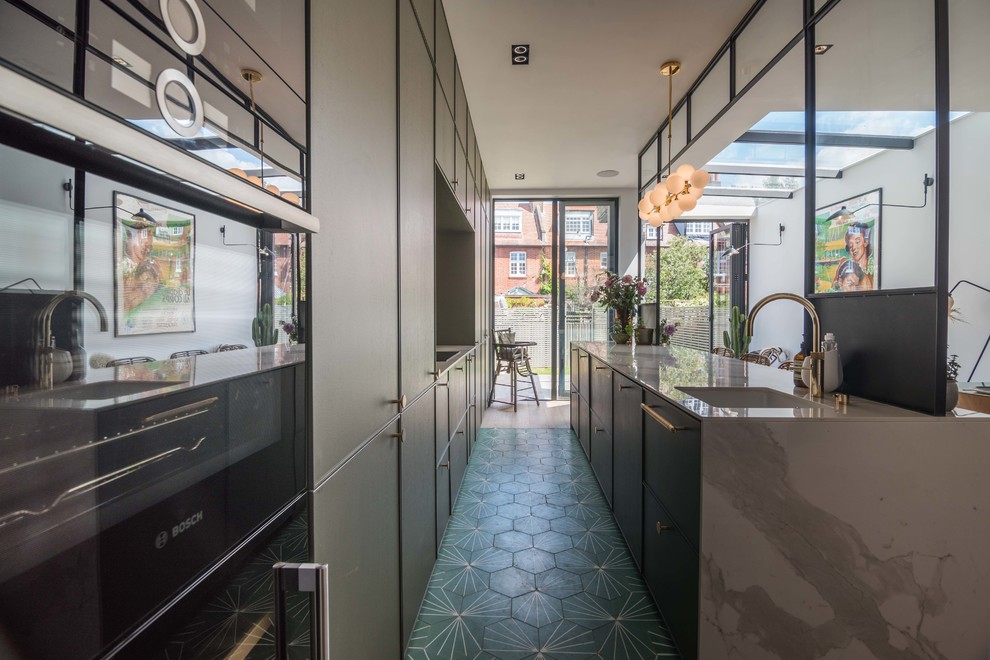 This is an example of a medium sized eclectic single-wall kitchen/diner in London with flat-panel cabinets, green cabinets, light hardwood flooring, an island and beige floors.