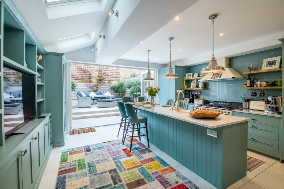 Inspiration for a traditional galley kitchen in London with shaker cabinets, green cabinets, green splashback, glass sheet splashback, an island, beige floors and white worktops.