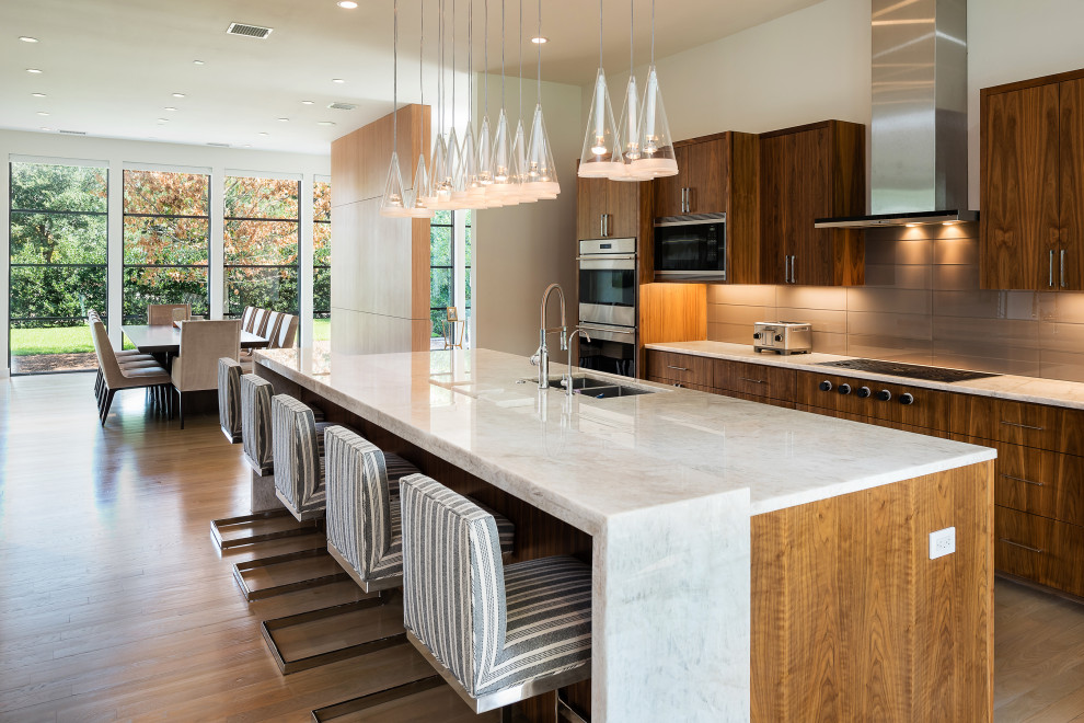 Example of a trendy galley light wood floor and beige floor kitchen design in Dallas with an undermount sink, flat-panel cabinets, medium tone wood cabinets, gray backsplash, stainless steel appliances, an island and white countertops