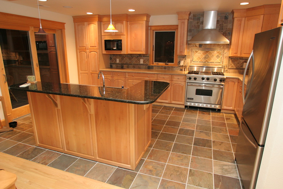 Example of a mid-sized classic l-shaped porcelain tile and brown floor eat-in kitchen design in Other with granite countertops, multicolored backsplash, stone tile backsplash, stainless steel appliances, an island, raised-panel cabinets and light wood cabinets