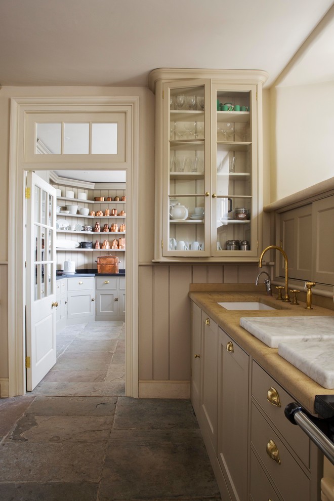 Design ideas for a traditional galley enclosed kitchen in London with a submerged sink, shaker cabinets, beige cabinets, wood worktops, beige splashback, wood splashback, coloured appliances, an island and grey floors.