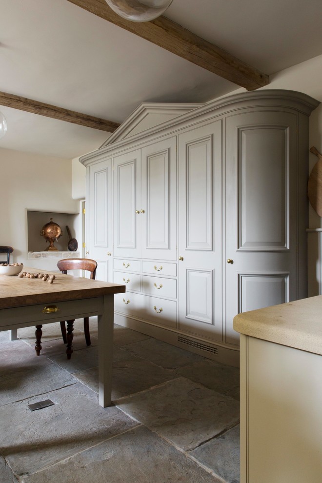 ロンドンにあるトラディショナルスタイルのおしゃれなキッチン (エプロンフロントシンク、シェーカースタイル扉のキャビネット、ベージュのキャビネット、ベージュキッチンパネル、木材のキッチンパネル、アイランドなし、グレーの床) の写真