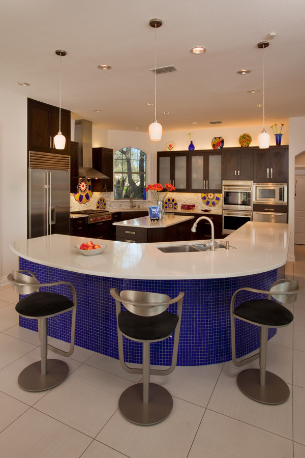 Example of a large eclectic l-shaped porcelain tile eat-in kitchen design in Austin with an undermount sink, shaker cabinets, dark wood cabinets, solid surface countertops, beige backsplash, ceramic backsplash, stainless steel appliances and two islands