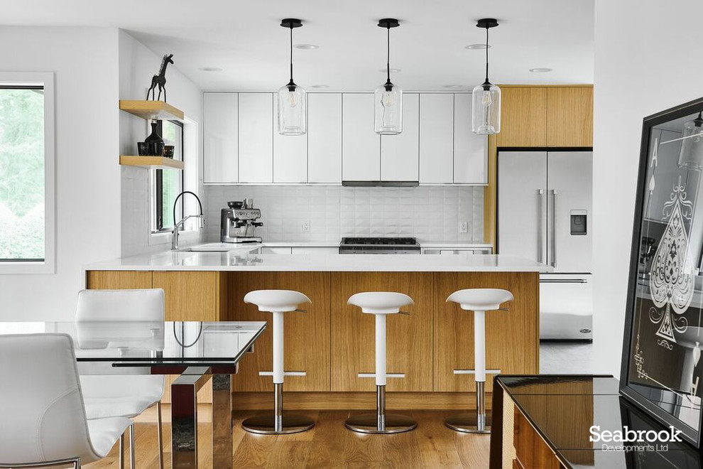 Inspiration for a medium sized contemporary u-shaped kitchen/diner in Vancouver with a submerged sink, flat-panel cabinets, white cabinets, engineered stone countertops, white splashback, ceramic splashback, stainless steel appliances, slate flooring, a breakfast bar, black floors and white worktops.