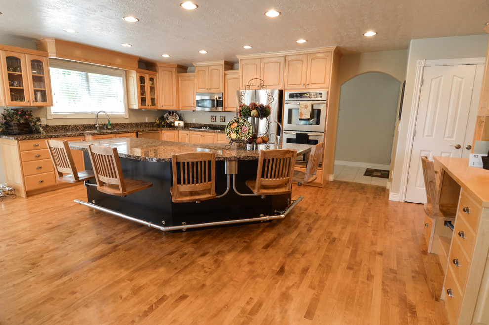 This is an example of a large classic l-shaped kitchen/diner in Salt Lake City with a submerged sink, recessed-panel cabinets, light wood cabinets, granite worktops, brown splashback, stainless steel appliances, light hardwood flooring and an island.