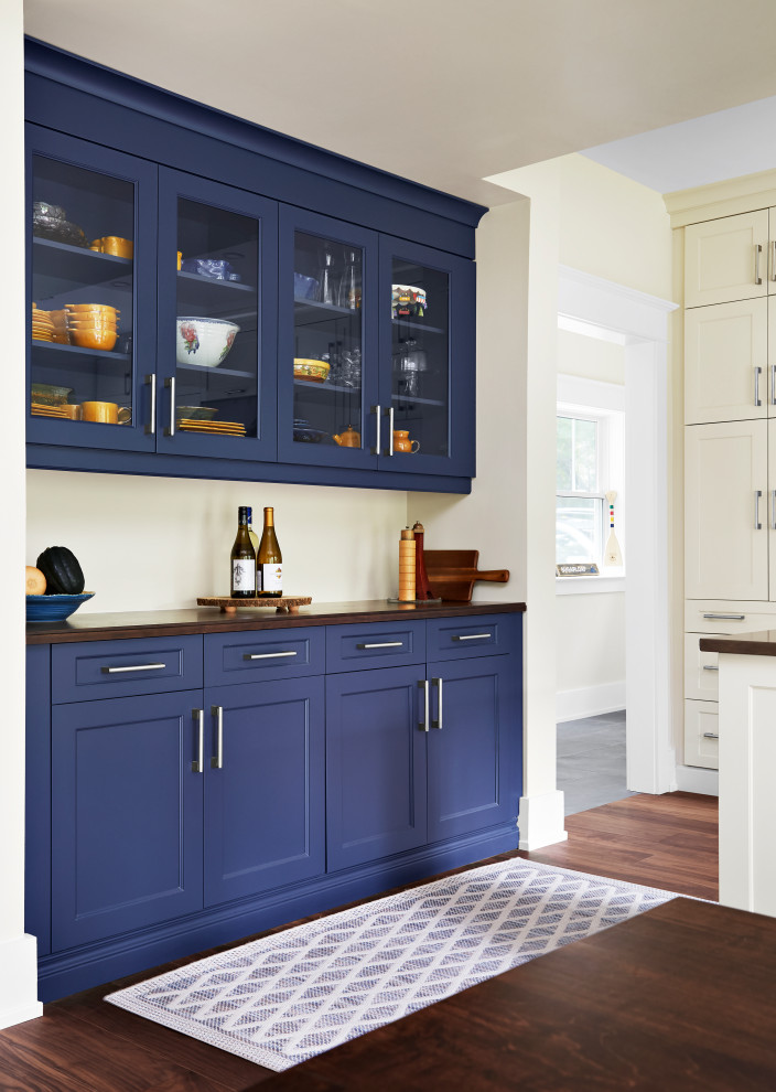 Immagine di una cucina american style con ante di vetro, ante blu, top in legno, pavimento in legno massello medio, pavimento marrone, top marrone e paraspruzzi giallo
