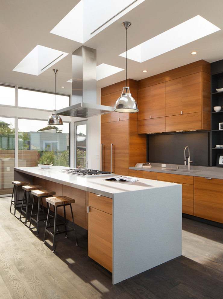 Cette image montre une cuisine design en bois brun avec un placard à porte plane, un plan de travail en quartz modifié, parquet foncé, îlot, un sol marron et un plan de travail gris.