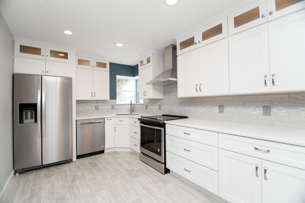 Idéer för att renovera ett mellanstort vintage vit vitt kök, med en undermonterad diskho, skåp i shakerstil, vita skåp, bänkskiva i kvarts, grått stänkskydd, glaspanel som stänkskydd, rostfria vitvaror, klinkergolv i porslin och grått golv
