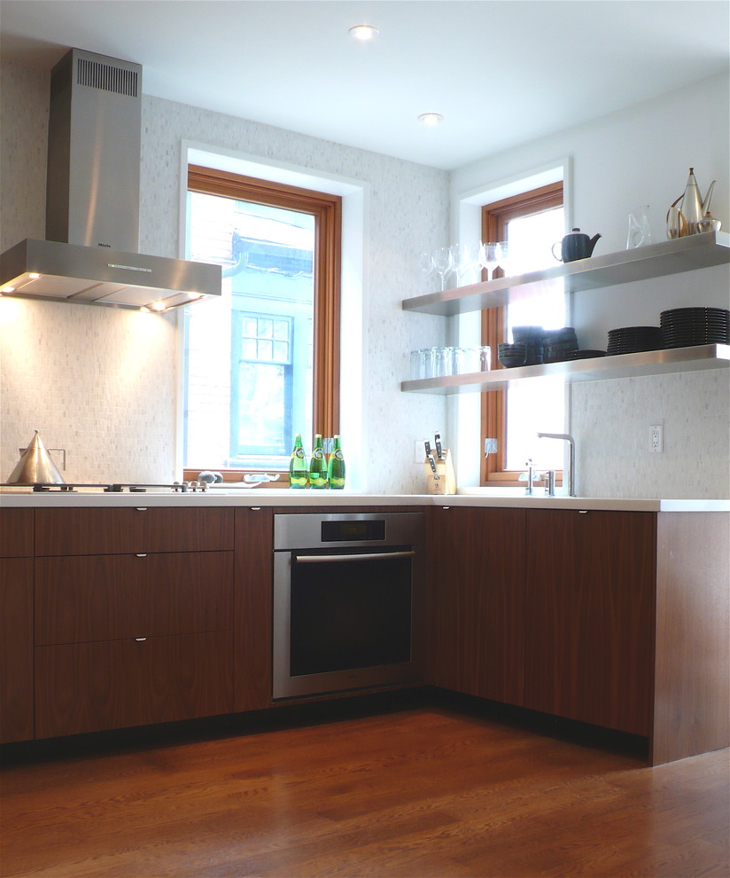 Immagine di una cucina minimalista con elettrodomestici in acciaio inossidabile, nessun'anta e ante in legno bruno