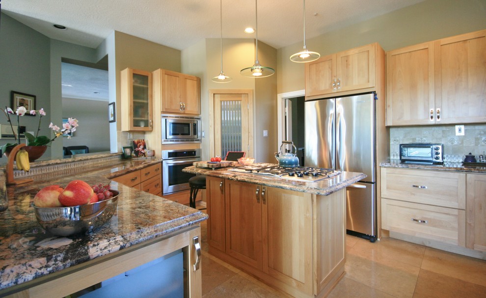 Modern inredning av ett u-kök, med en undermonterad diskho, skåp i shakerstil, skåp i ljust trä, granitbänkskiva, beige stänkskydd, spegel som stänkskydd och rostfria vitvaror