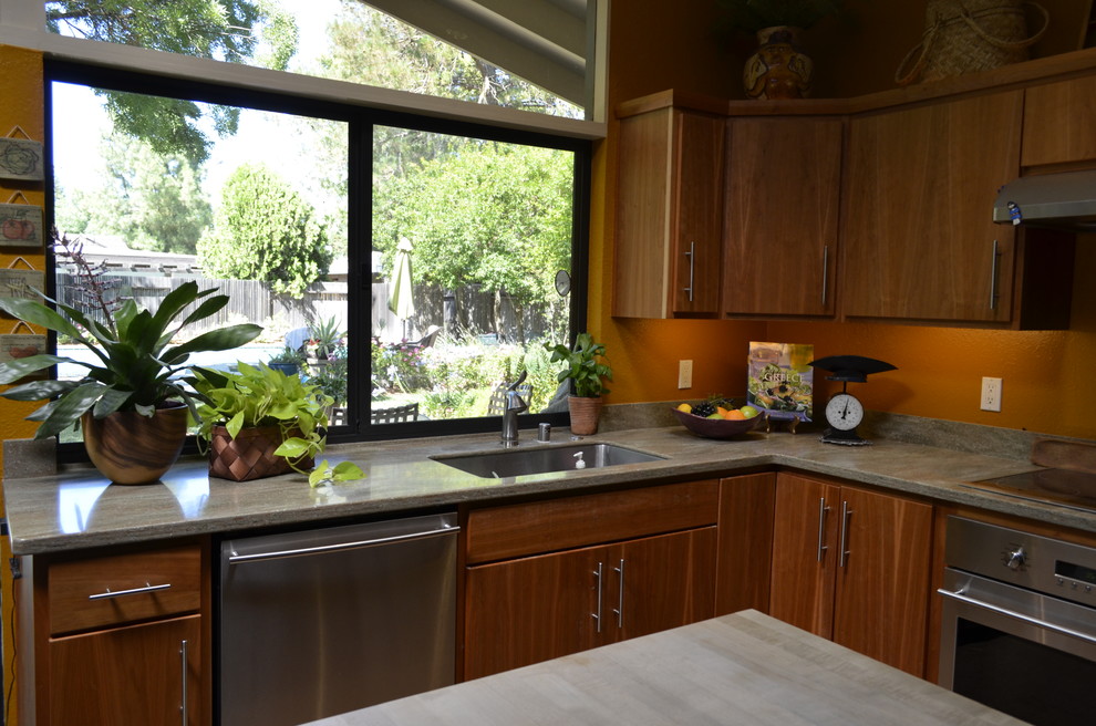 Photo of a medium sized modern l-shaped kitchen/diner in Sacramento with a submerged sink, flat-panel cabinets, medium wood cabinets, concrete worktops, orange splashback, stainless steel appliances and an island.