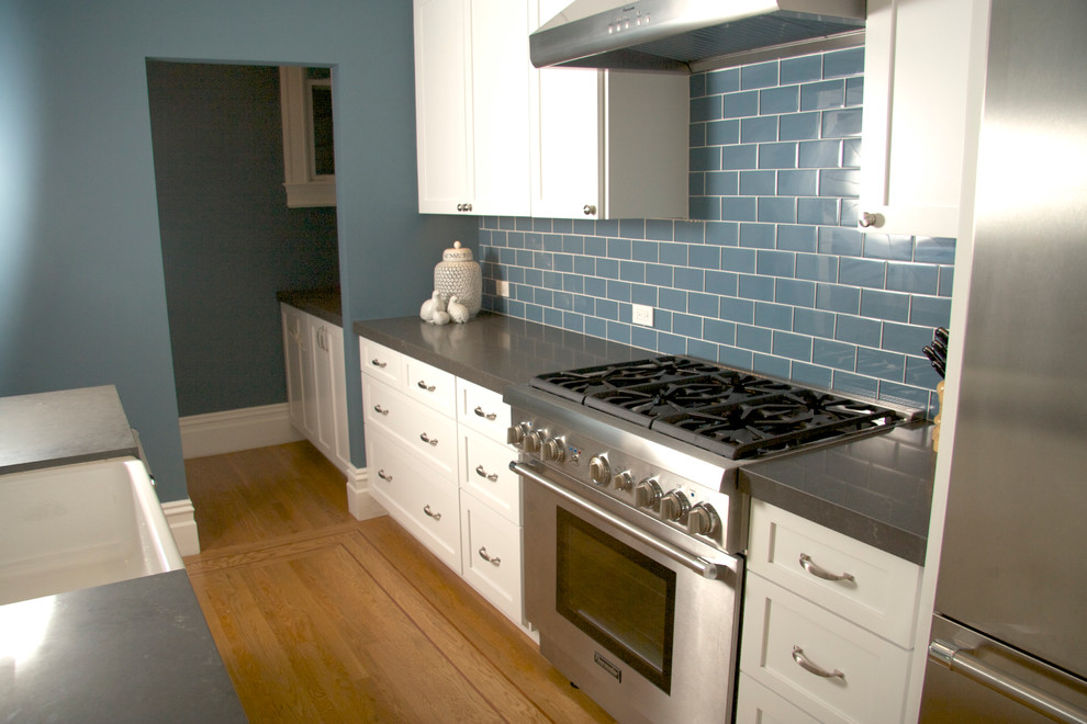 Foto på ett mellanstort vintage linjärt kök och matrum, med en integrerad diskho, skåp i shakerstil, vita skåp, bänkskiva i koppar, blått stänkskydd, stänkskydd i glaskakel, rostfria vitvaror och ljust trägolv