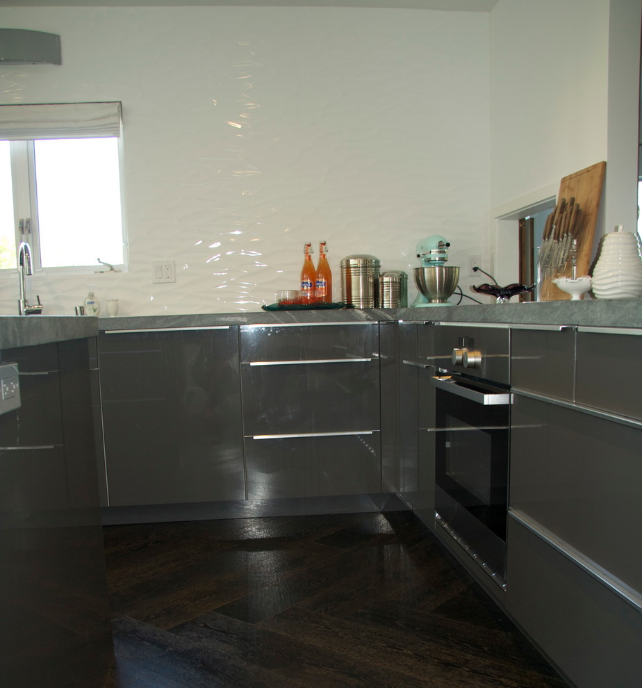 Foto på ett mellanstort retro kök, med en dubbel diskho, släta luckor, grå skåp, marmorbänkskiva, vitt stänkskydd, stänkskydd i porslinskakel, rostfria vitvaror, mörkt trägolv och en köksö