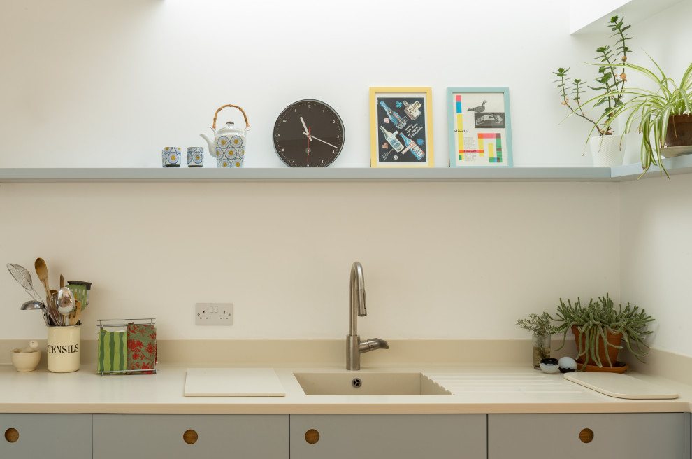 Inredning av ett modernt mellanstort beige beige kök, med en integrerad diskho, släta luckor, blå skåp, bänkskiva i koppar, vitt stänkskydd, rostfria vitvaror, klinkergolv i terrakotta, en köksö och rosa golv