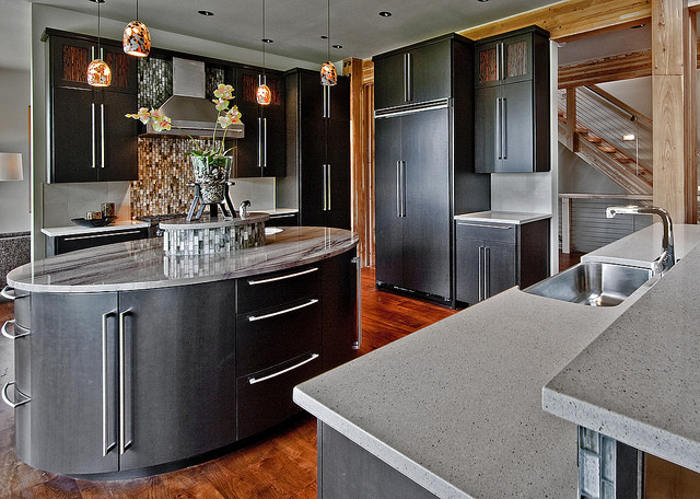 This is an example of a large contemporary u-shaped enclosed kitchen in Denver with a single-bowl sink, flat-panel cabinets, black cabinets, granite worktops, grey splashback, ceramic splashback, black appliances, medium hardwood flooring and an island.