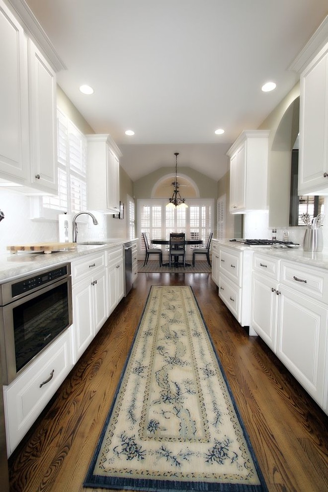 Inspiration for a timeless galley brown floor open concept kitchen remodel in Other with white cabinets, stainless steel appliances, no island and gray countertops