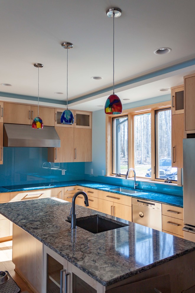 Foto på ett mellanstort funkis flerfärgad kök, med en enkel diskho, släta luckor, skåp i ljust trä, bänkskiva i återvunnet glas, blått stänkskydd, glaspanel som stänkskydd, rostfria vitvaror, en köksö, brunt golv och bambugolv