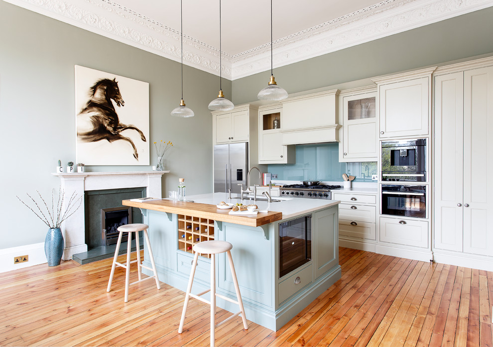 Inspiration for a timeless kitchen remodel in Edinburgh with green cabinets, solid surface countertops and an island