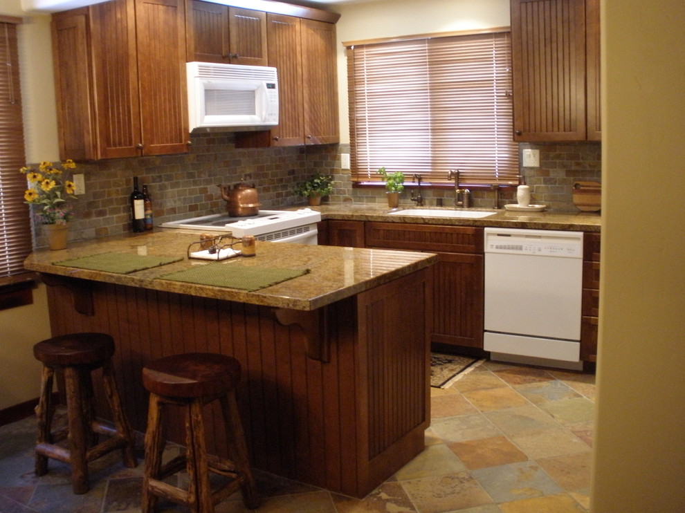 Inredning av ett klassiskt litet kök, med en nedsänkt diskho, skåp i mellenmörkt trä, marmorbänkskiva, vita vitvaror och en halv köksö