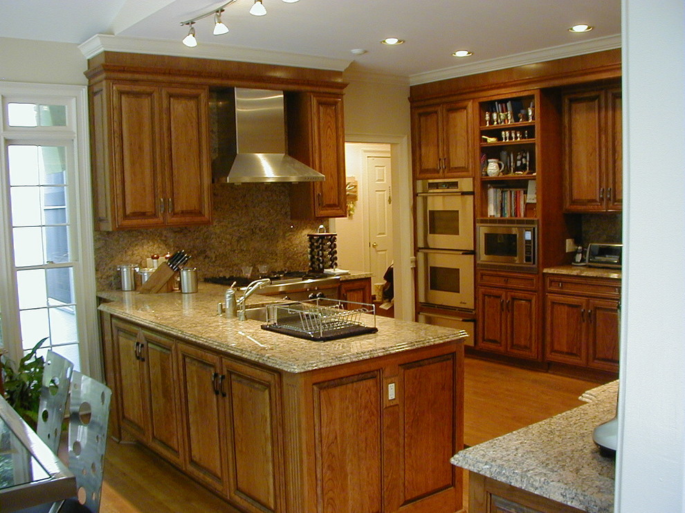Immagine di una cucina classica di medie dimensioni con lavello a doppia vasca, ante in legno scuro, top in marmo, elettrodomestici in acciaio inossidabile e pavimento in legno massello medio
