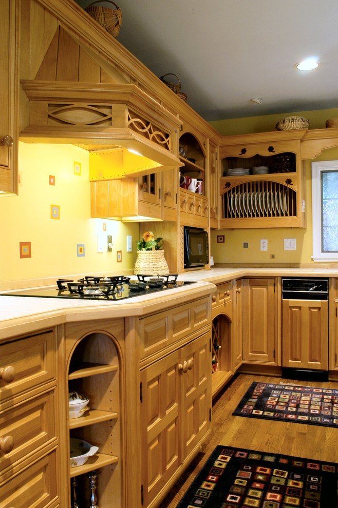 Foto di una cucina contemporanea con ante con bugna sagomata, ante in legno scuro, top piastrellato e elettrodomestici da incasso