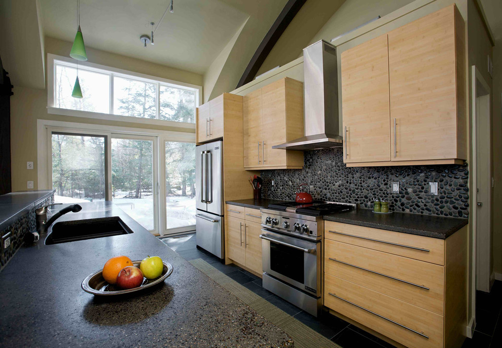 Foto di una cucina minimal di medie dimensioni con ante in legno chiaro, elettrodomestici in acciaio inossidabile, pavimento in ardesia, top in cemento e paraspruzzi grigio