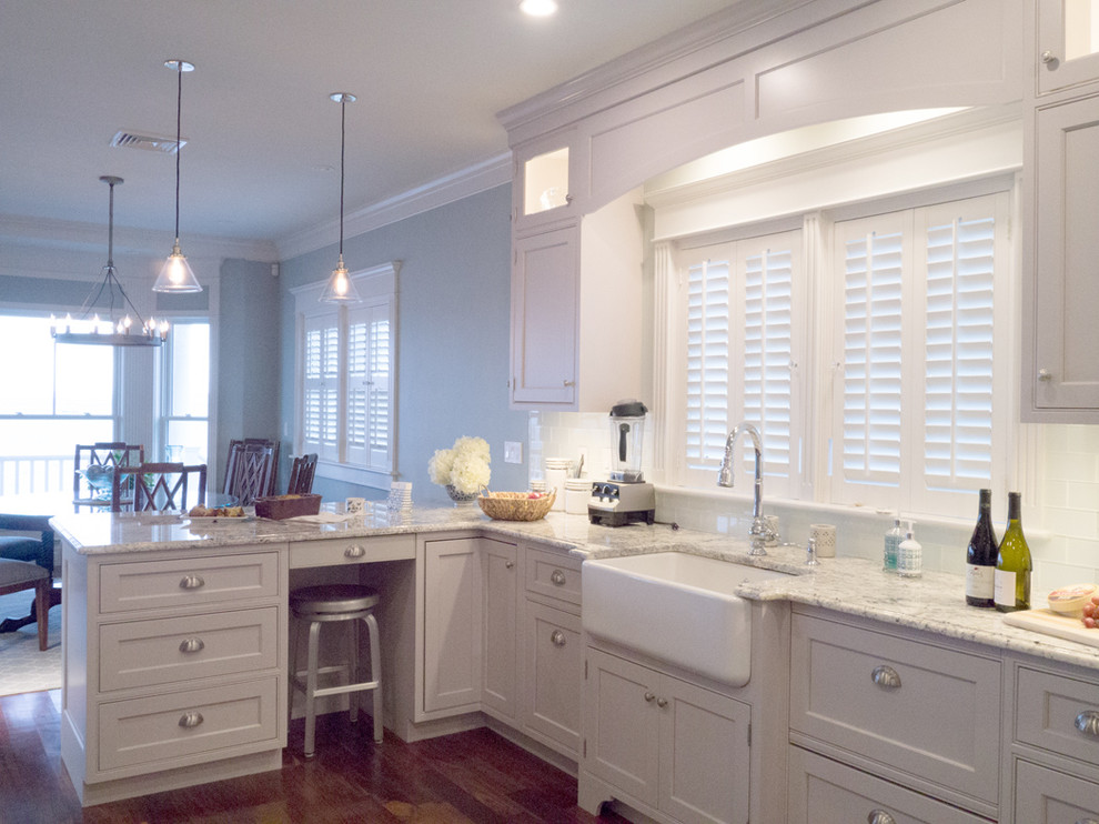 Large elegant l-shaped medium tone wood floor eat-in kitchen photo in Providence with a farmhouse sink, recessed-panel cabinets, white cabinets, granite countertops, white backsplash, glass tile backsplash and paneled appliances
