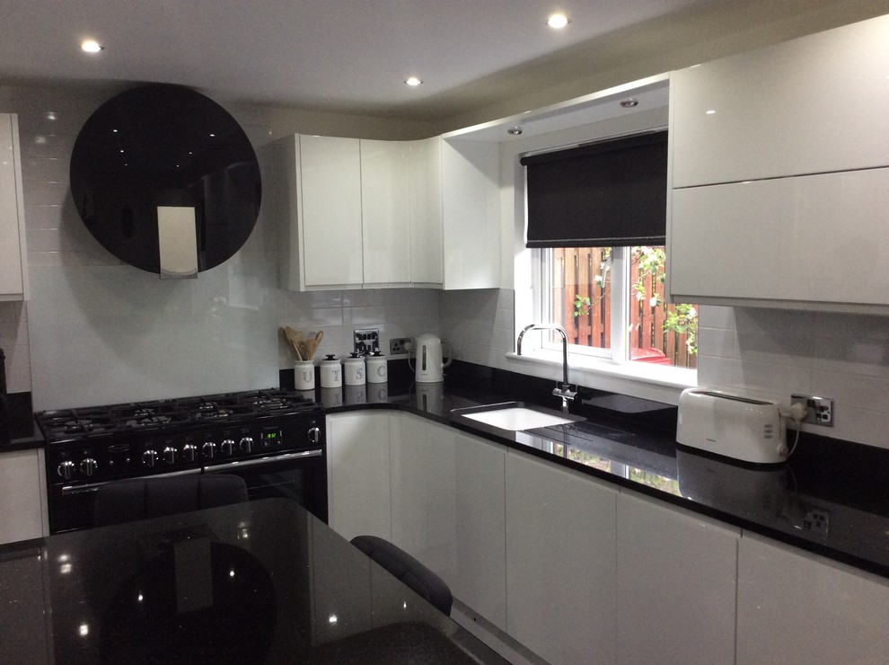 Large contemporary l-shaped kitchen in Glasgow with a built-in sink, white cabinets, granite worktops, yellow splashback, stainless steel appliances, ceramic flooring and an island.